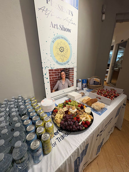Table with informational materials and a banner near the entrance of an art show.