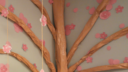 A handmade paper cherry blossom tree crafted with delicate pink paper blossoms attached to branches, creating a colorful and creative display symbolizing renewal and hope.