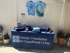 Outdoor table set up with Parents’ Foundation signage and materials at a community event.