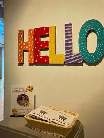 Large colorful “HELLO” letters on a wall near a guestbook display.