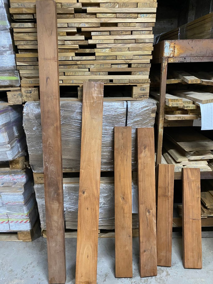 Several wood planks against a backdrop of lumber and pallets, Diamond Tropical Hardwoods
