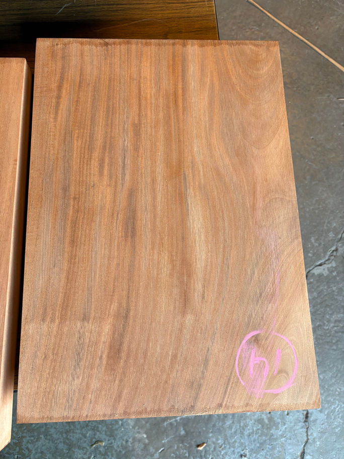 Close-up of premium figured mahogany boards, showing wood grain and pink markings, for sale.
