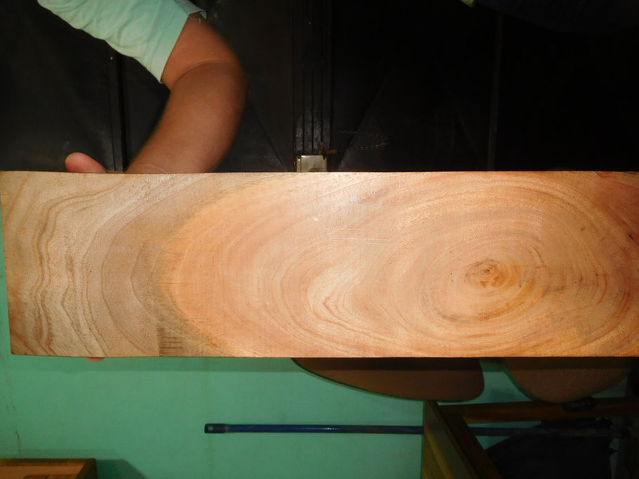 Person working with Highly Figured Mahogany Lumber, cutting wood with a saw.