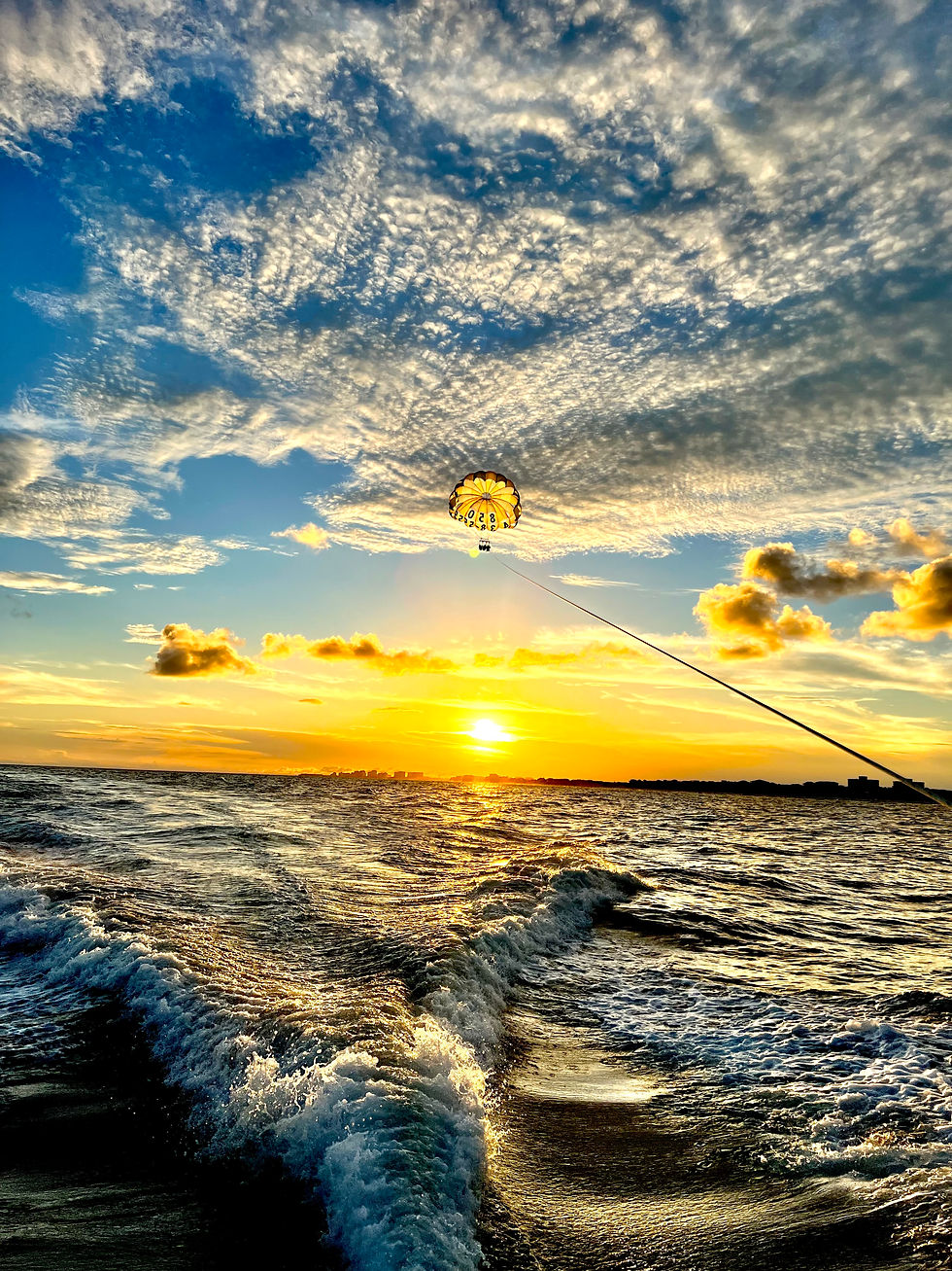 Eye-level view of a parasailing boat with colorful parachutes in the sky