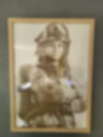 Portrait d'une femme pompier souriante, les bras croisés, casque, cadre en bois.