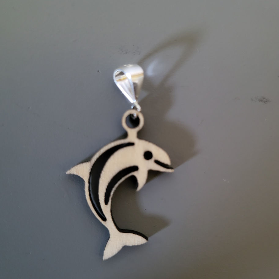 Pendentif dauphin en argent détaillé, avec motifs noirs, sur fond gris.