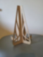 Support en bois clair, motif contemporain stylisé, sur table grise.