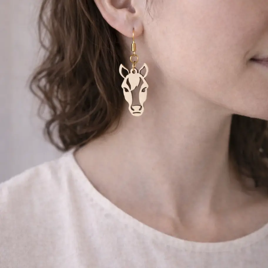 Femme portant une boucle d'oreille tête de cheval stylisée en bois.