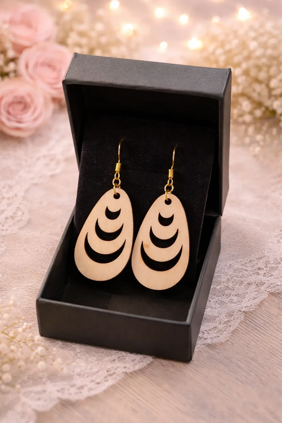 Paire de boucles d'oreilles pendantes ovales en bois dans une boîte cadeau noire.