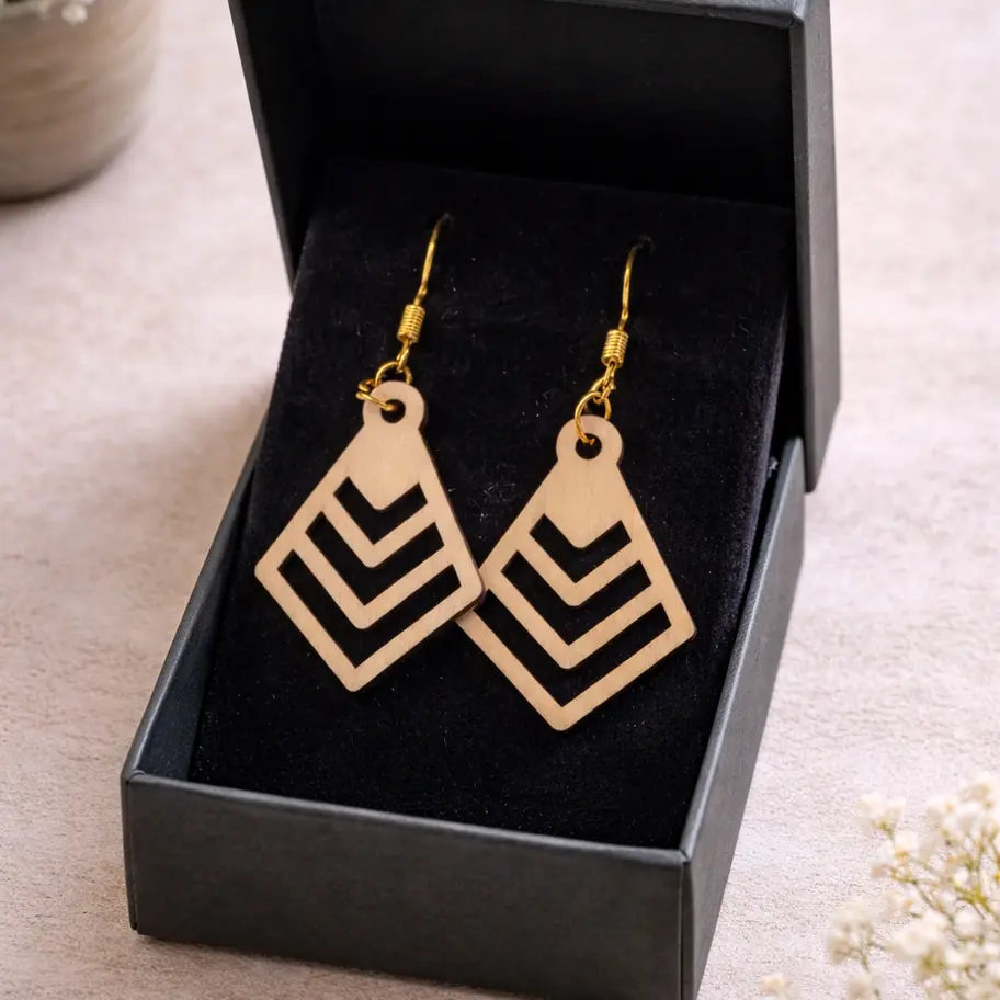 Boucles d'oreilles pendantes géométriques en bois clair présentées dans une boîte cadeau.