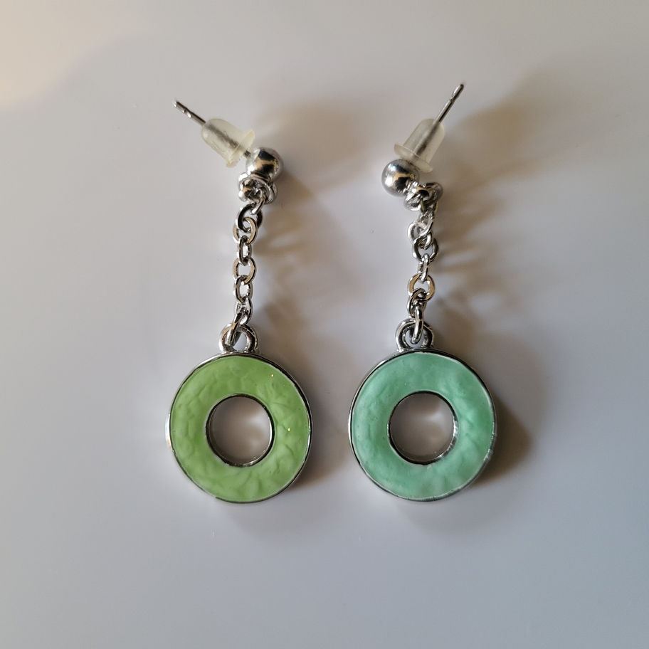 Boucles d'oreilles pendantes, cercles vert clair et bleu clair sur fond blanc.