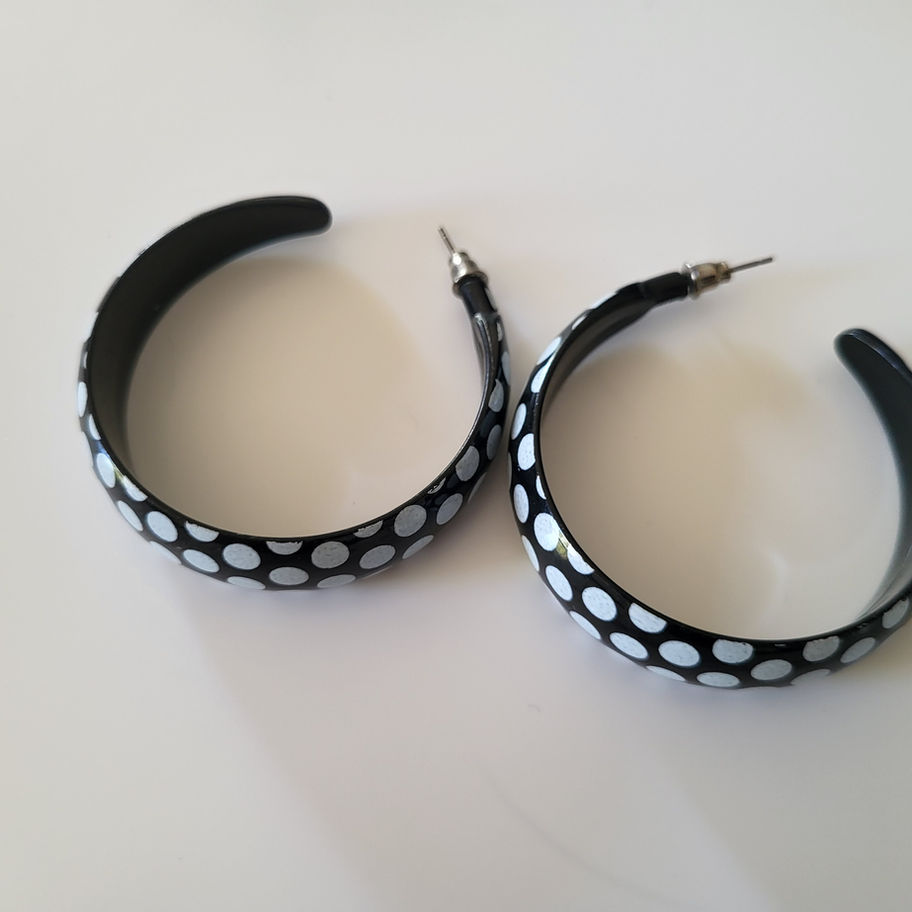 Paire de boucles d'oreilles créoles noires à pois blancs.