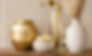 Bougie allumée, vases décoratifs dorés, herbe de pampa sur étagère en bois.