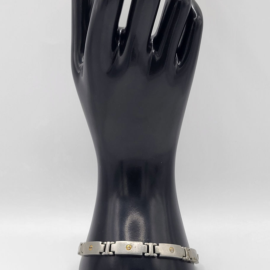 Bracelet à maillons argentés sur un présentoir en forme de main noire.