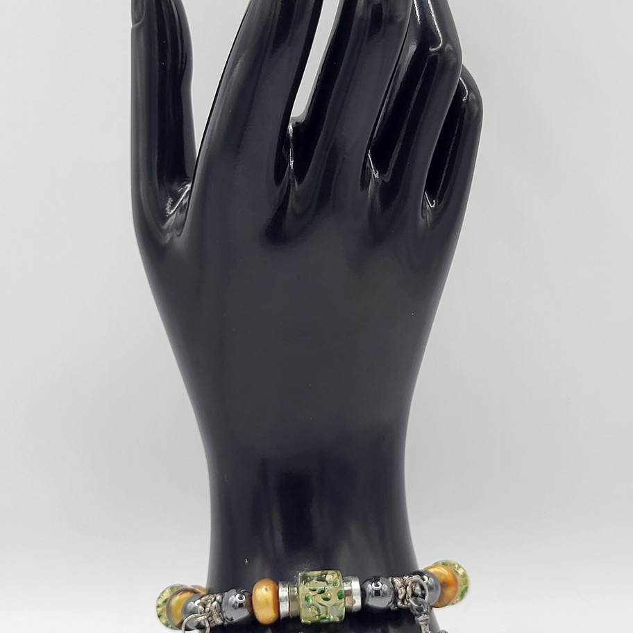 Main de mannequin noire présentant un bracelet avec perles variées et ornée.