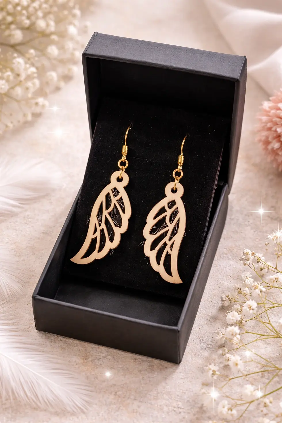 Paire de boucles d'oreilles dorées en forme d'ailes dans une boîte cadeau.