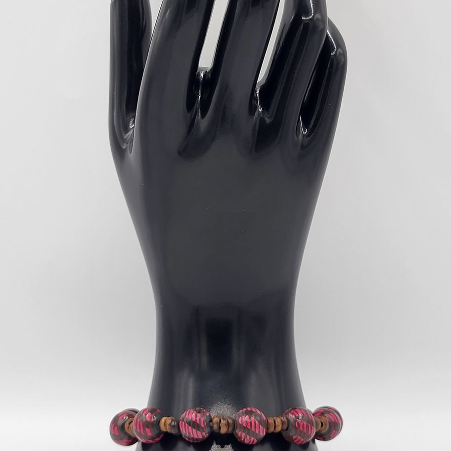 Bracelet perles marron-rouge sur mannequin main noire fond blanc.