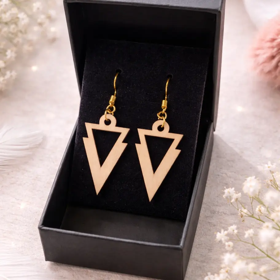 Boucles d'oreilles triangulaires géométriques en bois clair dans boîte cadeau noire.