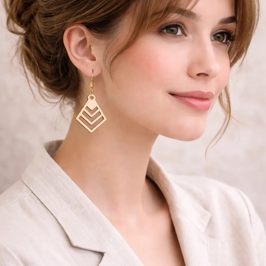 Femme souriante portant des boucles d'oreilles pendantes géométriques dorées élégantes.