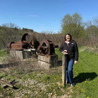 Woman standing in front of Mine equipment at Merry Christmas Mine Hill