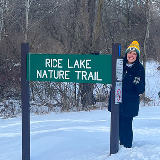 woman standing next to rice lake nature trail sign in winter in whitewater wisconsin