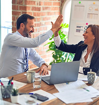 Man and woman team member laughing and high-fiving
