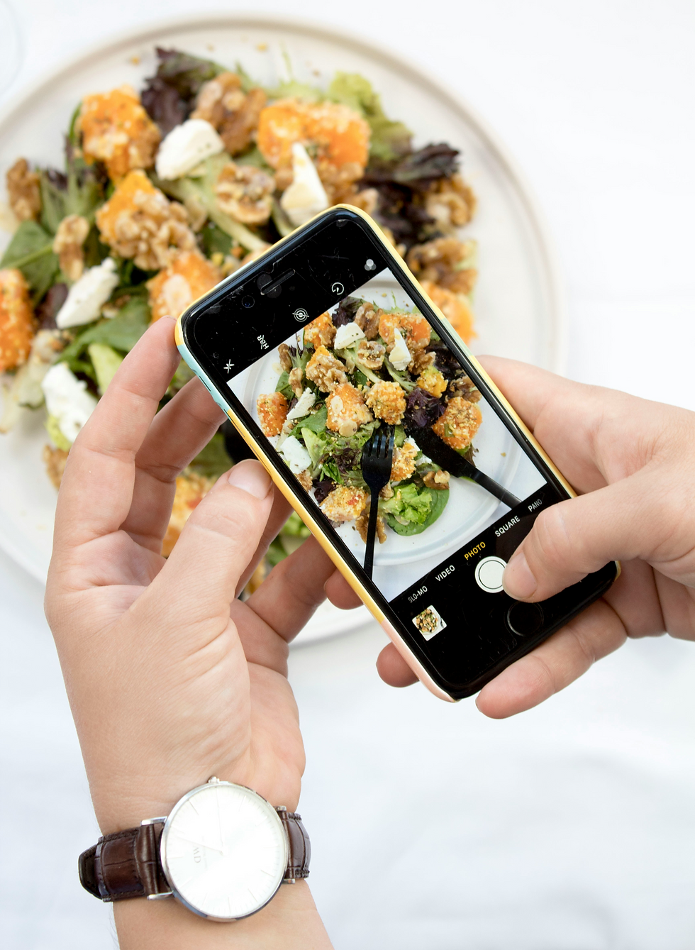 A person using iphone to take photo of a salad