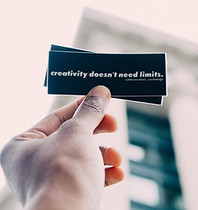 Hand holding up a piece of paper that says "Creativity doesn't need limits."