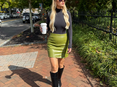 a fall outfit with a black top, green leather skirt and boots