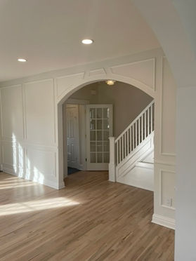 French doors and a white staircase framed by an archway in a New Jersey renovation