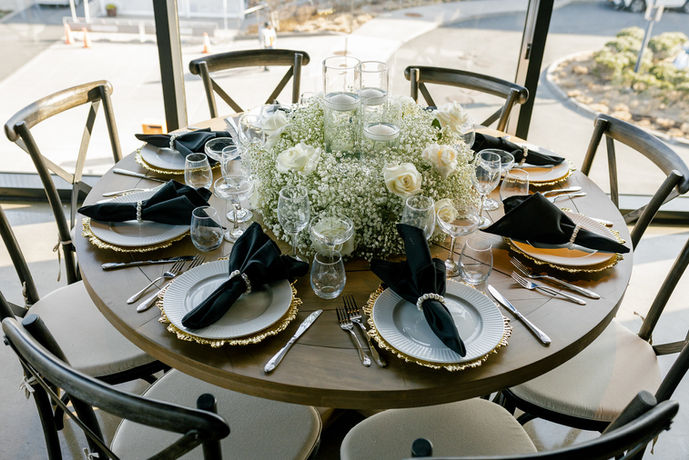 Round table set for event, white plates, floral centerpiece.