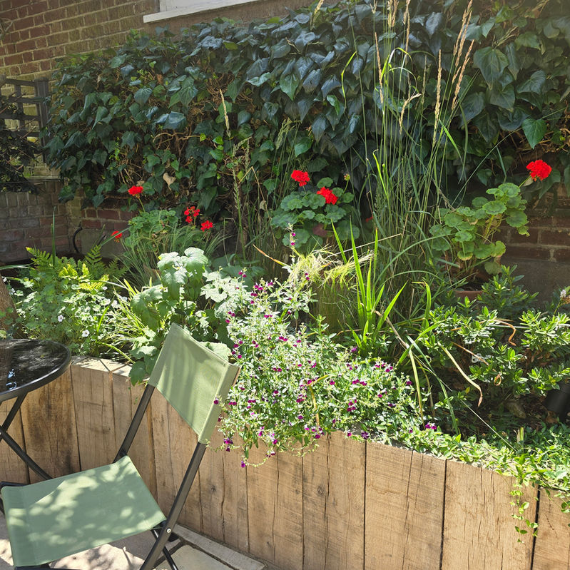 Vertical oak railway sleeper raised bed filled with seasonal plants adding height and texture to a Tooting, South London garden