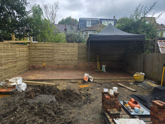Black rain tent in the middle of a Dulwich, South London garden covering clay pavers being laid during a landscaping project