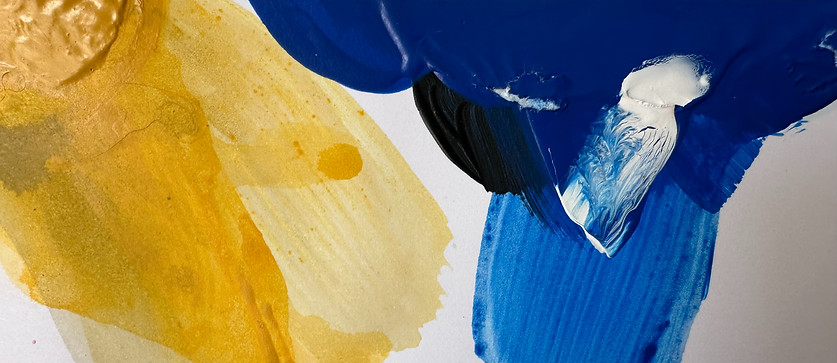 Zoomed in photo of a paint palette; colors include shades of yellow, blue, and white