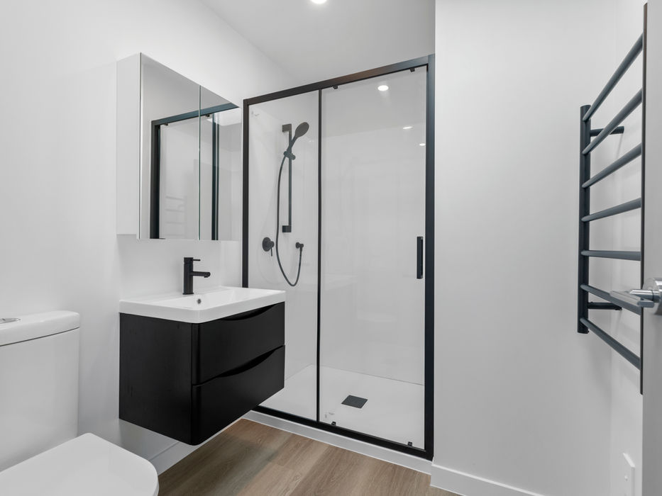 Modern bathroom with a black shower, sink, and towel rack.