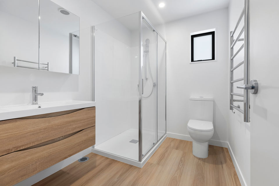 Modern bathroom with shower, toilet, sink, and wood cabinetry. 