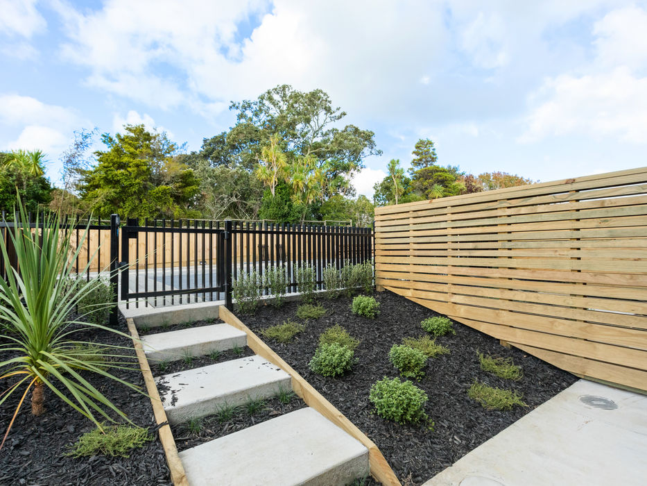Concrete steps lead to a black gate and wooden fence.