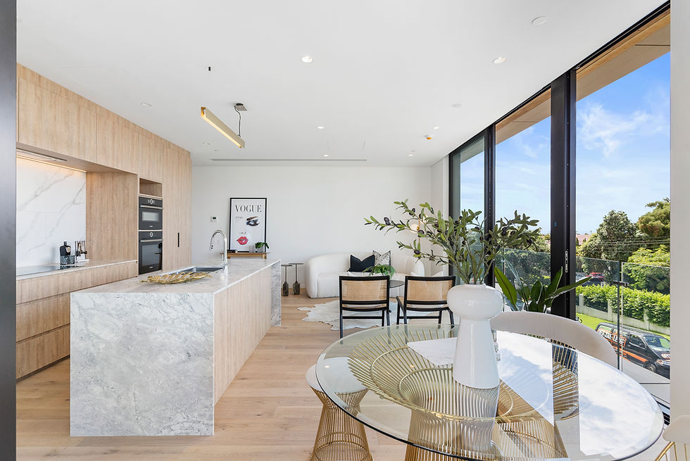 Modern kitchen and living room with large windows and white walls.