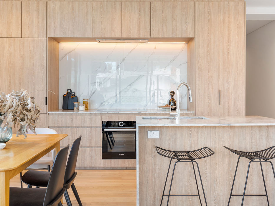 Modern kitchen with wooden cabinets, island, and bar stools; minimalist design