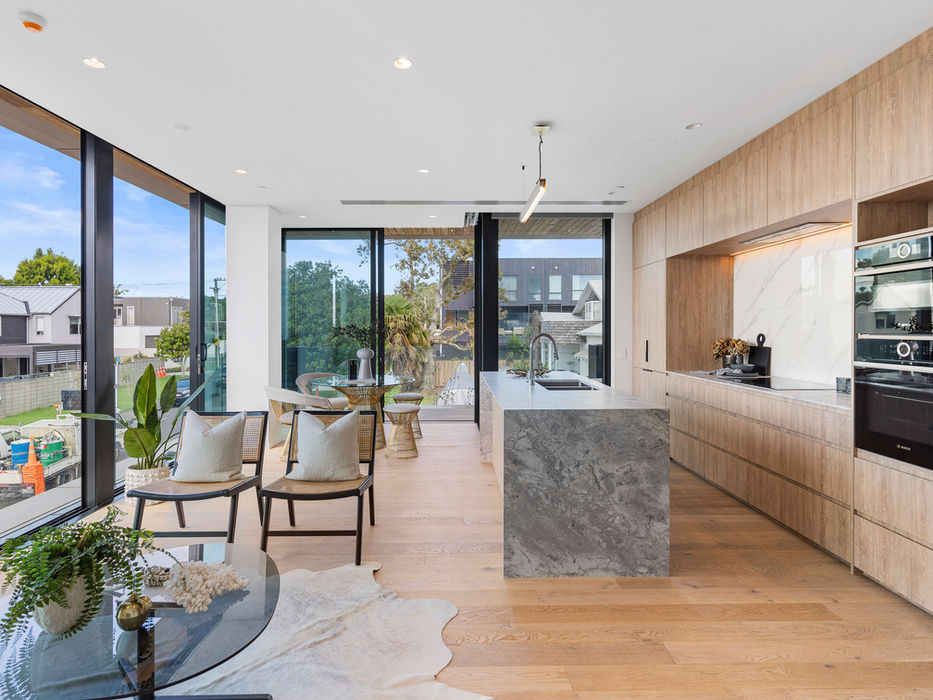 Modern kitchen and dining area with large windows and light wood cabinetry.