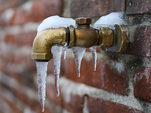 Frozen outdoor water pipe with ice buildup, showing how cold weather can cause burst pipes and water damage in residential homes.