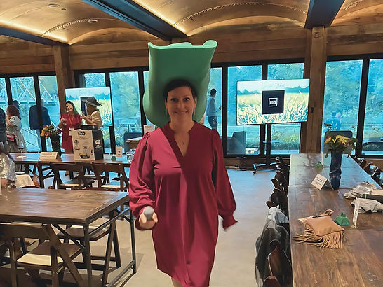 Whitney emceeing a large event wearing a huge green cowboy hat.