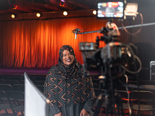 A woman being filmed as she smiles to the camera.