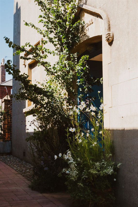 Flower & Branch - real plants together with cut flowers create an arch for a wedding ceremony at the chapel door in Alfriston east sussex. Sustainable floristry.