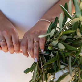 Braut hält Brautstrauß mit Ringen und Weiß. Hochzeitstag, Nahaufnahme, Hände.
