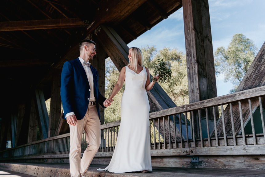 Brautpaar hält Händchen auf einer Holzbrücke, strahlend, kleiner Hochzeitsgeschichte