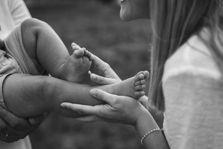 Intimate close-up of a baby's tiny feet being gently held by mommy's hands in Luxembourg's outdoors.