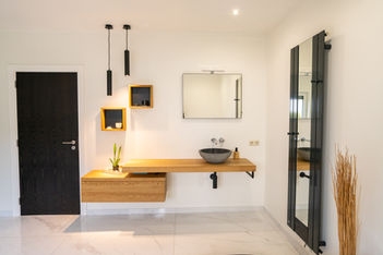 A modern bathroom sink and shelves with a brownish wooden color on a white-painted wall, in a Luxembourg property.