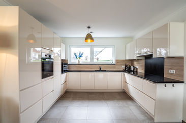 Spacious modern kitchen with white cabinets and clean lines, real estate photography Luxembourg