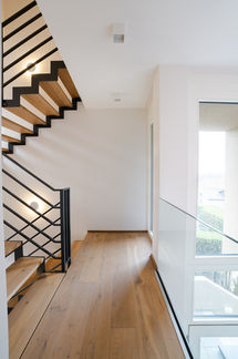 Bright staircase with wooden steps and glass railing, interior photography Luxembourg modern home